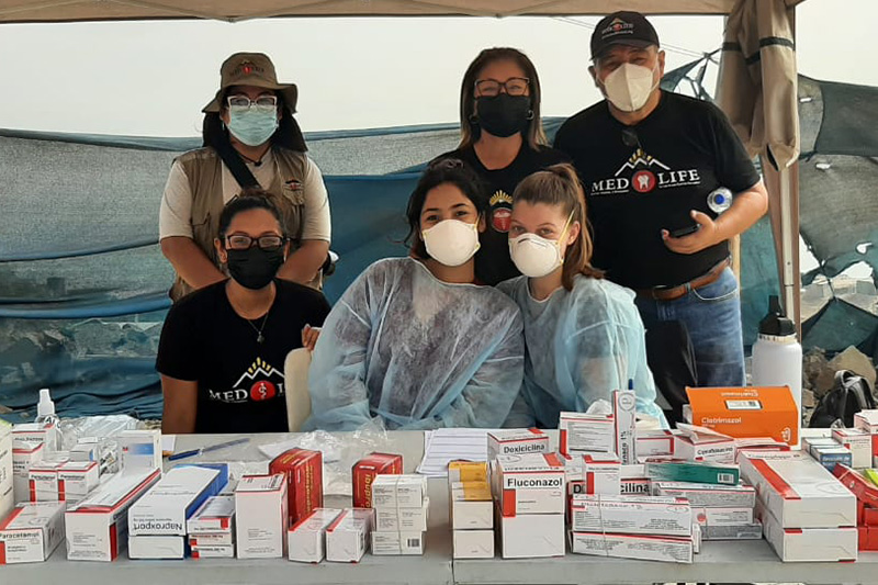 Students in masks and scrubs wait to distribute medicines in Lima, Peru