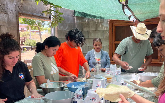 Rigo Aldama leads 7 students in making torillas from scratch on a large table.