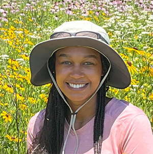 Closeup of Camile Taylor outside in field of yellow daisies.